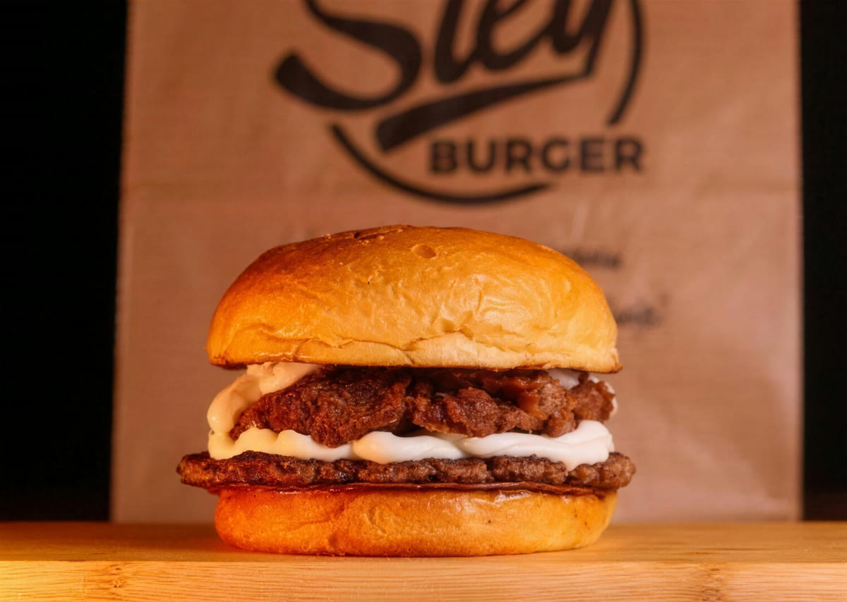 Germany Burger na tábua de madeira, com a sacola da Sley Burguer ao fundo